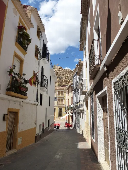 Calle estrecha en Busot con edificios blancos y balcones decorados.