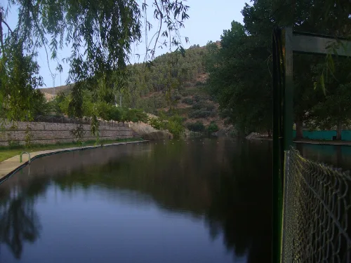 Blick auf die Garganta de Descuernacabras mit ruhigem Wasser und Vegetation.