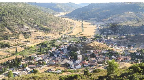 Panoramic view of Alhóndiga with houses, fields, and mountains.