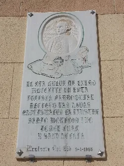 Plaque with portrait and text on the church facade.