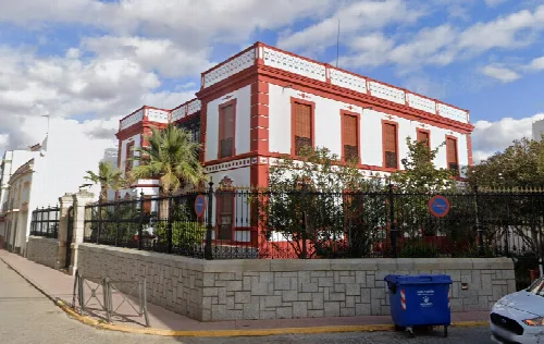 Gebäude mit weißen und roten Wänden, umgeben von Pflanzen und einem schmiedeeisernen Zaun in Santa Marta de los Barros.