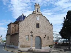 Facade of San Roque hermitage with blue dome and brick walls.