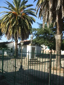 Bronzestatue eines Soldaten, umgeben von Palmen und Bäumen in Villanueva de la Sierra.