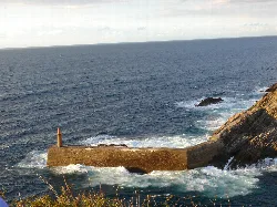 Vista del puerto con rompeolas y faro en la costa de Asturias