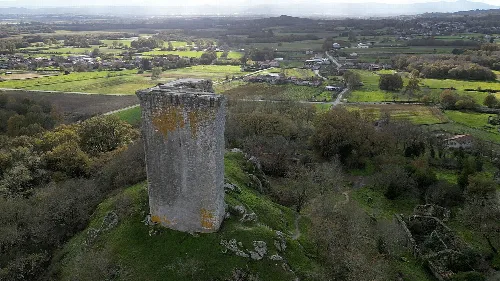 Alte Turm auf ländlicher Landschaft mit Dorf im Hintergrund.