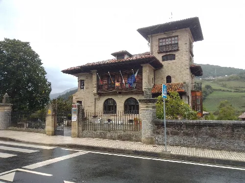 Edificio de piedra con balcón y banderas en Tama, Cillorigo de Liébana.