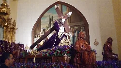 Religiöse Statue in einer Kirche mit Gemälden und Figuren im Hintergrund.
