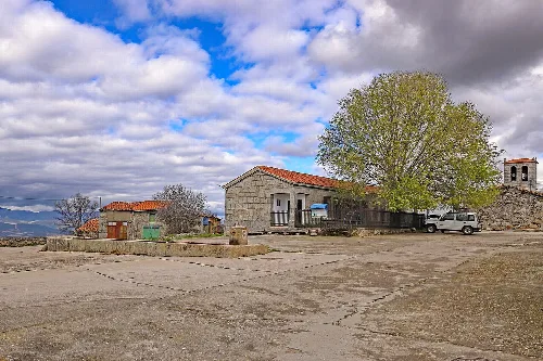 Plaza con fuente, árbol grande y edificios en Pinedas, Salamanca.