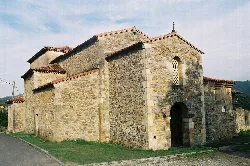 Stone church with bell tower and arched door in Pravia, Asturias.