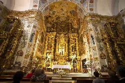Innenraum einer Kirche mit goldenem Altar und Golddekorationen.