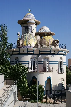 Casa con formas curvadas y techos en forma de setas, con colores pastel y detalles artísticos.