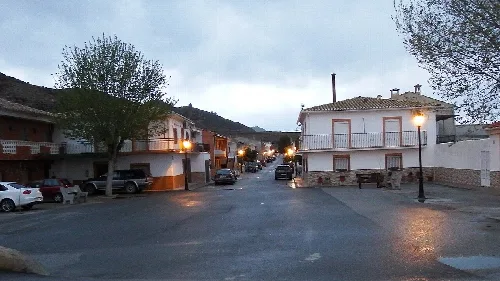 Straßen mit weißen Häusern, Bäumen und Straßenlaternen in Alicún de Ortega.