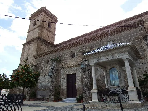 Iglesia de piedra con torre y fachada, en la plaza de Purchena.