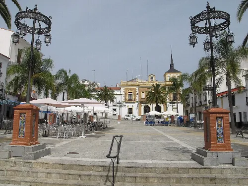 Plaza Ramón y Cajal mit Cafés, Palmen und Straßenlaternen in Valverde del Camino.