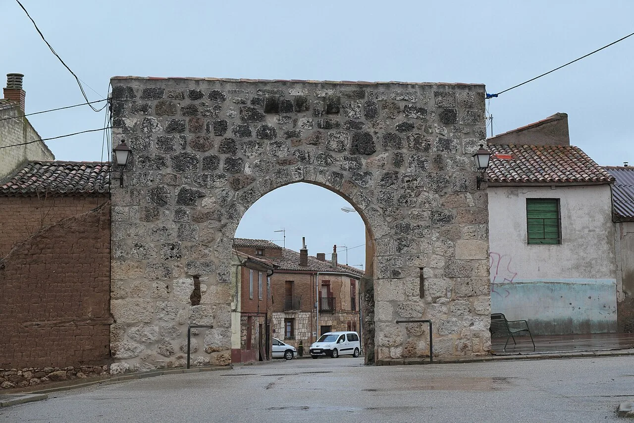 Stone city gate in Villahoz with houses around.