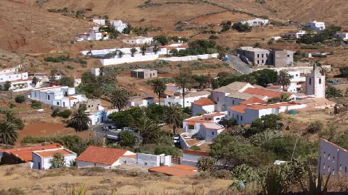Blick auf weiße Häuser, Palmen und trockene Hügel in Betancuria, Fuerteventura.