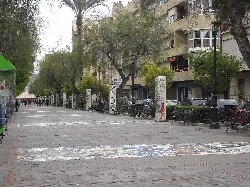 A pedestrian street with trees, benches, and residential buildings in Cieza.