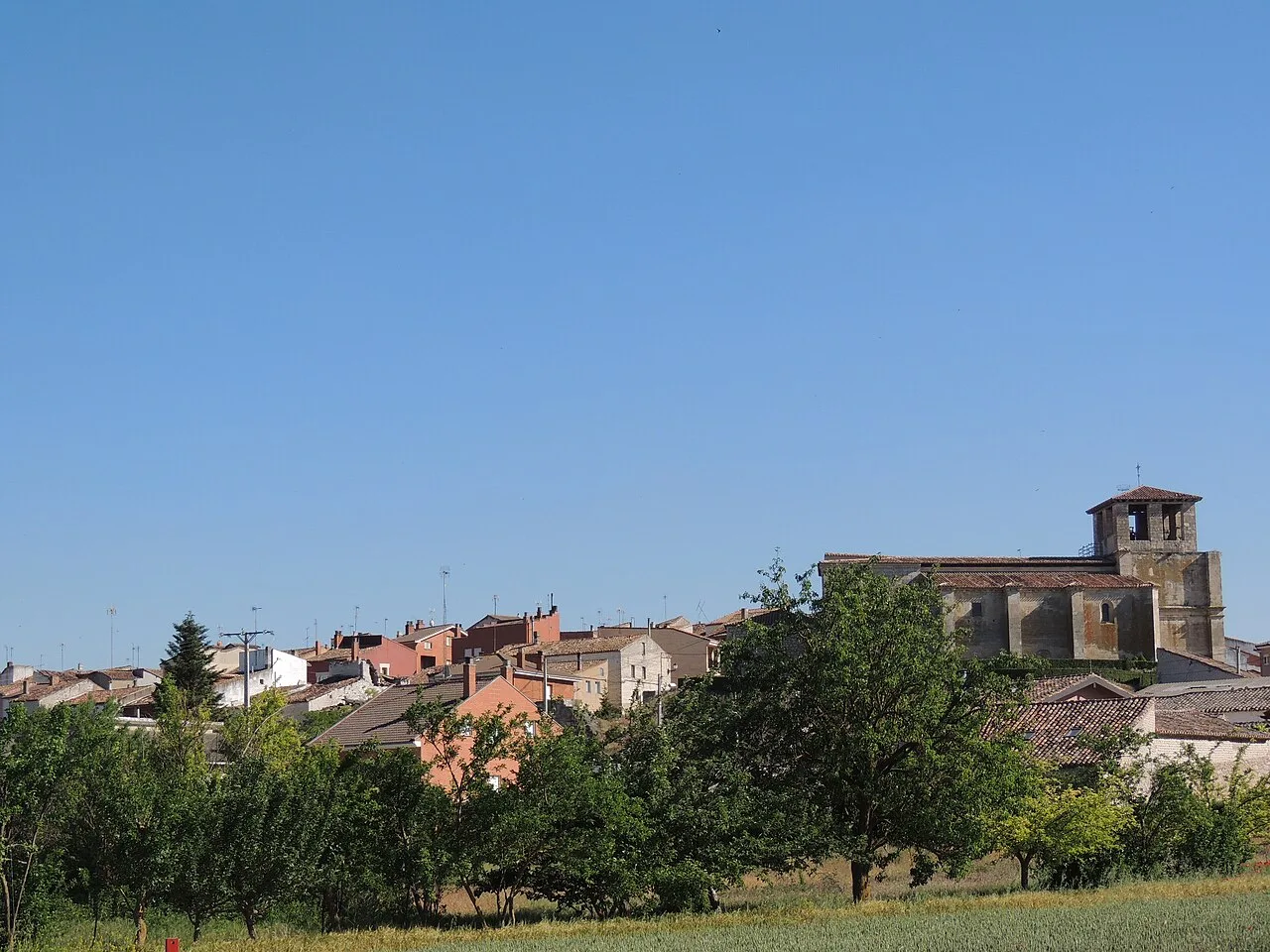 Landscape of Villafruela with houses and trees under a blue sky.