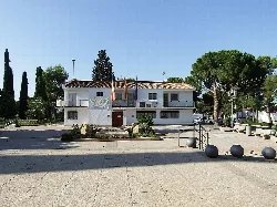 Edificio blanco en la plaza de Loriguilla con árboles y bolas decorativas.