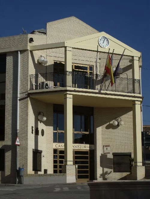Rathausgebäude mit Uhr und Flaggen an der Fassade.