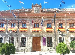 Fassade des Rathauses von Sonseca mit Flaggen und Holztür.