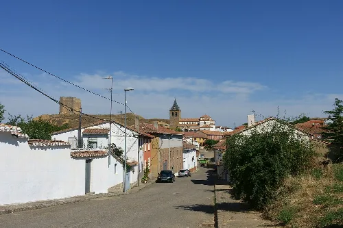 Ansicht eines Dorfes mit Häusern, Kirche und Mauern im Hintergrund.