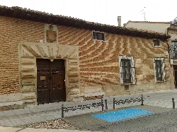 Facade of a building with a wooden door and barred windows in Marchamalo.