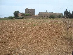 Torre de Na Blanca in Torreblanca with dirt field and building in the background.
