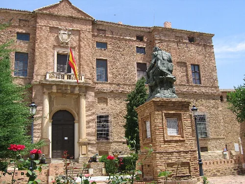 Edificio de piedra con bandera y estatua en el jardín.
