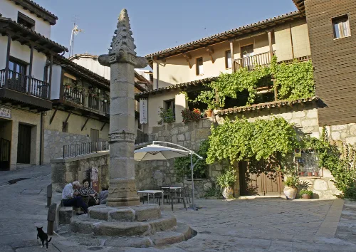 Platz mit Brunnen und Stein- und Holzhäusern in Valverde de la Vera.