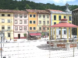Square with colorful buildings and kiosk structure in Sotrondio, Asturias.