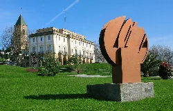 Iron sculpture in a park with historic church and town hall.