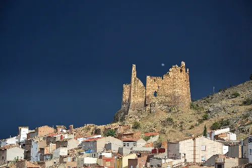 Ruined castle atop Jarque de Moncayo with colorful houses in the foreground.