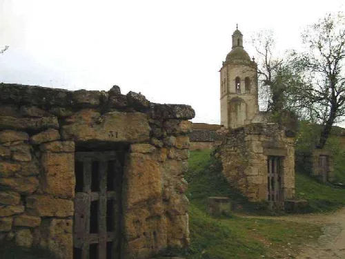 Stone cellars with San Andrés Church in the background in Zazuar, Burgos.