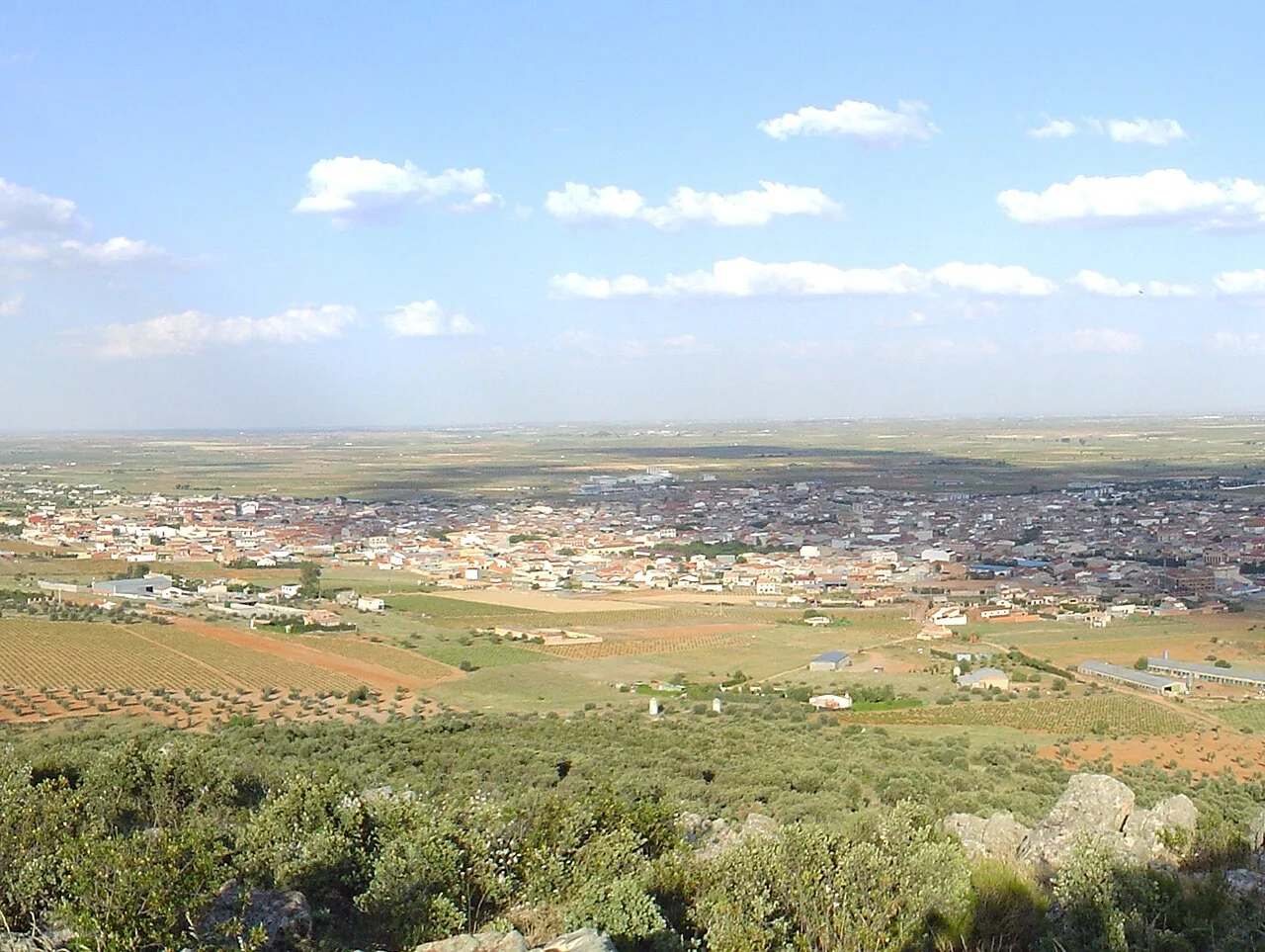 Weites Landschaftsbild mit Stadt und Feldern in Villarrubia de los Ojos von einem Hügel aus.