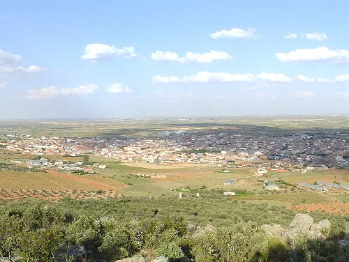 Weites Landschaftsbild mit Stadt und Feldern in Villarrubia de los Ojos von einem Hügel aus.