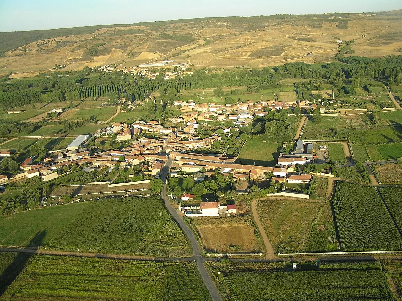 Aerial view of a village with green fields and houses in a rural landscape.