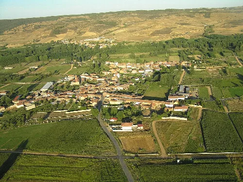 Luftaufnahme eines Dorfes mit grünen Feldern und Häusern in einer ländlichen Landschaft.