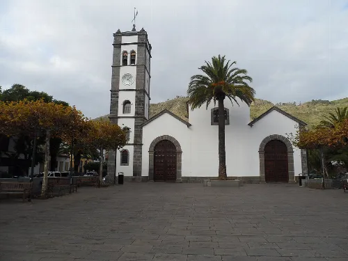 Kirche von San Marcos Evangelista mit Turm und Palmen auf dem Platz.