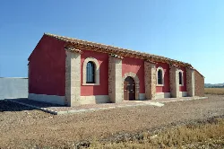 Kapelle San Andrés in Mainar, mit roten Wänden und Gitterfenstern.