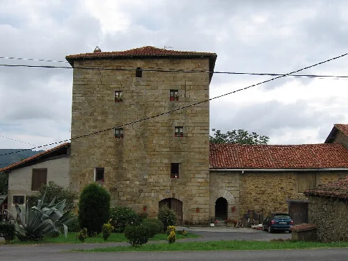 Torre de piedra con ventanas pequeñas y techo de tejas rojas en Lezama.