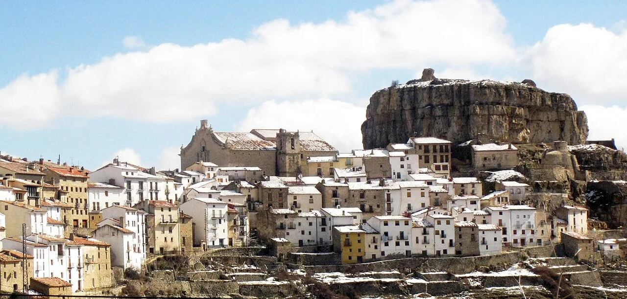 Vista de un pueblo con casas blancas y una gran roca en el fondo