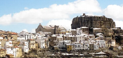 Vista de un pueblo con casas blancas y una gran roca en el fondo