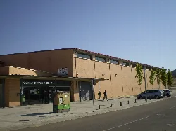 Gebäude des Sportzentrums mit Bäumen und Personen am Eingang.