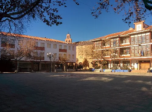 Plaza con edificios y una iglesia en el fondo en Castellar de Santiago.