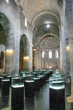 Vitrinen in einem archäologischen Museum mit Steingemäuern und Bögen.