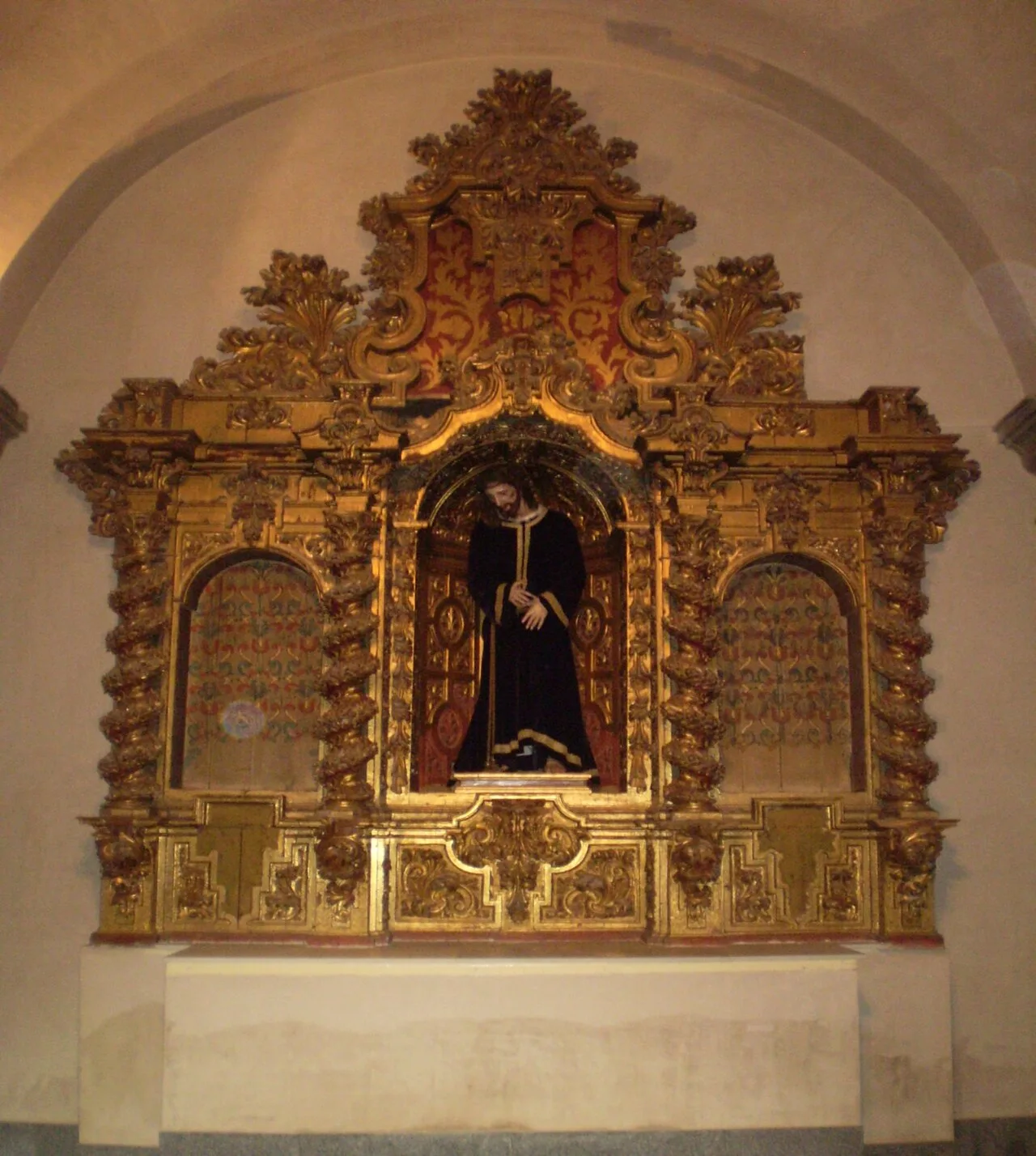 Golden altarpiece with a figure of the Nazarene in the center and decorative details.