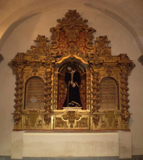 Goldenes Altarbild mit einer Figur des Nazarener in der Mitte und dekorativen Details.