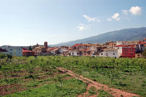 White and red houses in Gotor with field and mountains in the background.