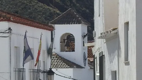 Fachadas blancas y campanario en una calle de Armuña de Almanzora.